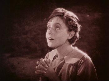 Movie still from “Peter Pan” (1924), directed by Herbert Brenon – An old photo of a woman praying with her eyes closed; Medium shot, High angle