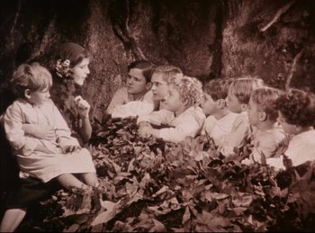 Movie still from “Peter Pan” (1924), directed by Herbert Brenon – A group of people sitting in a pile of leaves; Wide shot, High angle