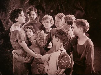 Movie still from “Peter Pan” (1924), directed by Herbert Brenon – A group of young children gathered around a woman; Medium shot, High angle