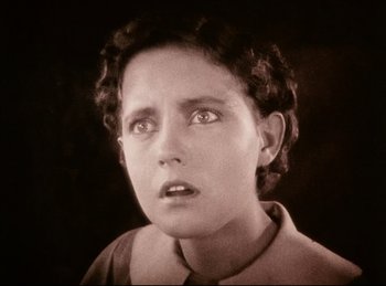 Movie still from “Peter Pan” (1924), directed by Herbert Brenon – A young woman looking at the camera in a black and white photo; Close Up shot, High angle