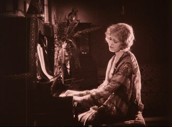 Movie still from “Peter Pan” (1924), directed by Herbert Brenon – A woman sitting in front of an upright piano; Medium shot, Low angle
