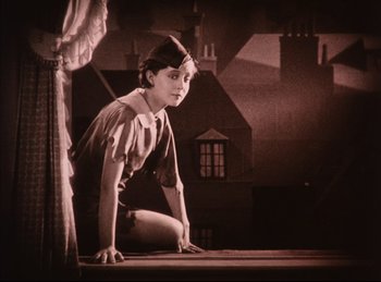 Movie still from “Peter Pan” (1924), directed by Herbert Brenon – A young girl sitting on the ground in front of a building; Medium shot, Low angle