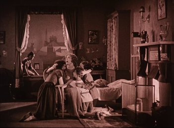 Movie still from “Peter Pan” (1924), directed by Herbert Brenon – A group of people sitting on a bed in a room; Wide shot, High angle