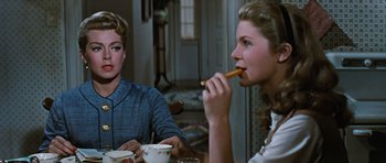 Movie still from “Peyton Place” (1957), directed by Mark Robson – Two women sitting at a dining table eating food; Medium shot, Over the shoulder angle