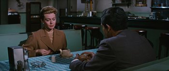 Movie still from “Peyton Place” (1957), directed by Mark Robson – A man and a woman are sitting at a table; Medium shot, Over the shoulder angle