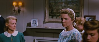 Movie still from “Peyton Place” (1957), directed by Mark Robson – A woman standing in front of a fireplace in front of a painting; Close Up shot, Over the shoulder angle