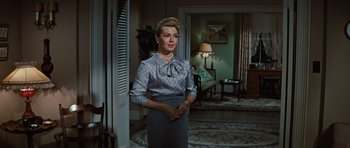Movie still from “Peyton Place” (1957), directed by Mark Robson – A woman standing in front of a door in a living room; Medium shot, Low angle