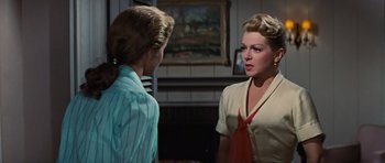 Movie still from “Peyton Place” (1957), directed by Mark Robson – Two women are talking in front of a painting; Medium shot, Over the shoulder angle