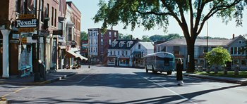 Movie still from “Peyton Place” (1957), directed by Mark Robson – A bus driving down a street next to buildings; Extreme Wide shot, High angle