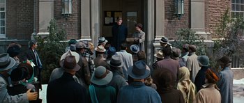 Movie still from “Peyton Place” (1957), directed by Mark Robson – A group of people standing outside of a brick building; Wide shot, High angle