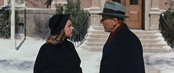Movie still from “Peyton Place” (1957), directed by Mark Robson – An older man and a young woman standing next to each other on the sidewalk; Medium shot, Over the shoulder angle