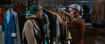 Movie still from “Peyton Place” (1957), directed by Mark Robson – Two women are looking at clothes on a rack; Medium shot, Over the shoulder angle