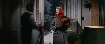 Movie still from “Peyton Place” (1957), directed by Mark Robson – A woman in a gray coat holding a red box; Medium shot, Low angle