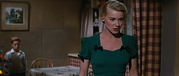 Movie still from “Peyton Place” (1957), directed by Mark Robson – A woman in a green dress standing in front of a table; Close Up shot, Over the shoulder angle