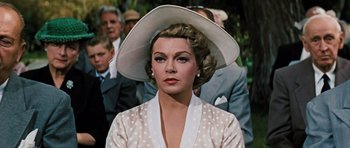 Movie still from “Peyton Place” (1957), directed by Mark Robson – A woman in a polka dot dress and a white hat; Close Up shot, Over the shoulder angle
