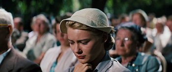 Movie still from “Peyton Place” (1957), directed by Mark Robson – A person wearing a hat with people in the background; Close Up shot, Low angle