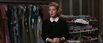 Movie still from “Peyton Place” (1957), directed by Mark Robson – A woman standing in front of a rack of clothes; Medium shot, Over the shoulder angle