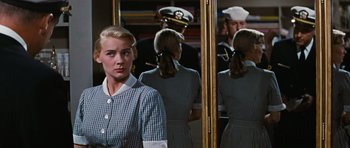 Movie still from “Peyton Place” (1957), directed by Mark Robson – A woman standing in front of a mirror in front of a uniform; Close Up shot, Over the shoulder angle