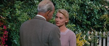 Movie still from “Peyton Place” (1957), directed by Mark Robson – A man and a woman standing next to each other in front of bushes; Close Up shot, Over the shoulder angle