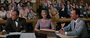 Movie still from “Peyton Place” (1957), directed by Mark Robson – A woman sitting at a table in front of a group of people; Medium shot, High angle