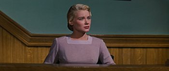 Movie still from “Peyton Place” (1957), directed by Mark Robson – A woman sitting in front of a wooden desk; Close Up shot, Low angle
