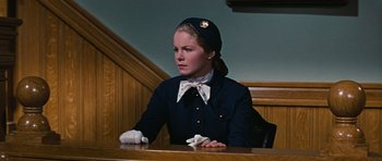 Movie still from “Peyton Place” (1957), directed by Mark Robson – A woman sitting at a table in a courtroom; Medium shot, Low angle