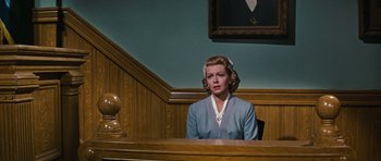 Movie still from “Peyton Place” (1957), directed by Mark Robson – A woman sitting at a table in front of a wooden wall; Medium shot, Low angle