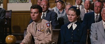 Movie still from “Peyton Place” (1957), directed by Mark Robson – A group of people sitting next to each other in a courtroom; Medium shot, Low angle
