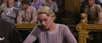 Movie still from “Peyton Place” (1957), directed by Mark Robson – A woman sitting in front of a table with other people in the background; Medium shot, Low angle