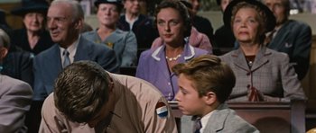 Movie still from “Peyton Place” (1957), directed by Mark Robson – A man and a woman in a crowd of people; Medium shot, Over the shoulder angle