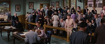 Movie still from “Peyton Place” (1957), directed by Mark Robson – A group of people standing around in a room; Wide shot, High angle