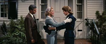 Movie still from “Peyton Place” (1957), directed by Mark Robson – Two women and a man are hugging outside a house; Medium shot, Over the shoulder angle