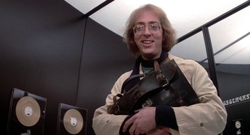 Movie still from “Phantom of the Paradise” (1974), directed by Brian De Palma – A man holding a bag in a room with black walls; Medium shot, Low angle