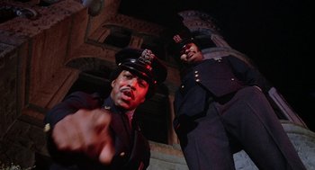 Movie still from “Phantom of the Paradise” (1974), directed by Brian De Palma – A couple of men standing next to each other in uniform; Medium shot, Low angle