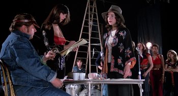 Movie still from “Phantom of the Paradise” (1974), directed by Brian De Palma – Two women and a man are standing in front of a ladder; Medium shot, Low angle