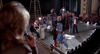 Movie still from “Phantom of the Paradise” (1974), directed by Brian De Palma – A group of people standing around a stage; Wide shot, High angle