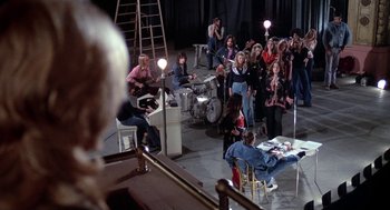 Movie still from “Phantom of the Paradise” (1974), directed by Brian De Palma – A group of people sitting around a stage; Wide shot, High angle