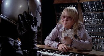 Movie still from “Phantom of the Paradise” (1974), directed by Brian De Palma – A woman sitting at a table with a keyboard; Close Up shot, Over the shoulder angle