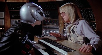 Movie still from “Phantom of the Paradise” (1974), directed by Brian De Palma – A woman and a man are playing a musical instrument together; Medium shot, Over the shoulder angle