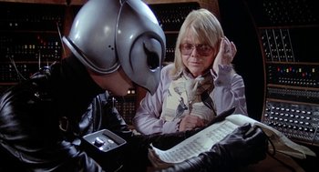 Movie still from “Phantom of the Paradise” (1974), directed by Brian De Palma – An older woman and a younger man are sitting in front of a computer screen; Medium shot, Over the shoulder angle
