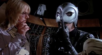 Movie still from “Phantom of the Paradise” (1974), directed by Brian De Palma – A person wearing a helmet and gloves talking to another person; Close Up shot, Over the shoulder angle