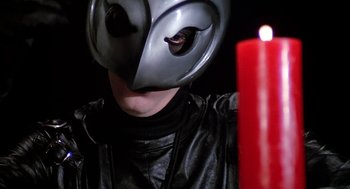 Movie still from “Phantom of the Paradise” (1974), directed by Brian De Palma – A person with a helmet on and a candle in the background; Close Up shot, Low angle