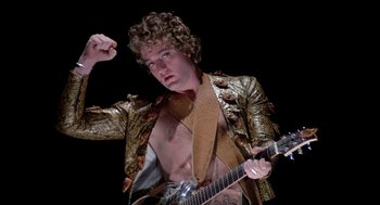 Movie still from “Phantom of the Paradise” (1974), directed by Brian De Palma – A man in a gold jacket holding a guitar; Medium shot, Low angle