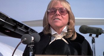 Movie still from “Phantom of the Paradise” (1974), directed by Brian De Palma – An older woman wearing sunglasses and a black jacket; Close Up shot, Low angle