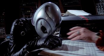 Movie still from “Phantom of the Paradise” (1974), directed by Brian De Palma – A person wearing a black leather glove and a metal helmet; Close Up shot, High angle