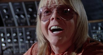 Movie still from “Phantom of the Paradise” (1974), directed by Brian De Palma – An older woman wearing sunglasses and a red shirt; Close Up shot, Low angle