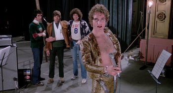 Movie still from “Phantom of the Paradise” (1974), directed by Brian De Palma – A group of men standing next to each other on a stage; Medium shot, Low angle