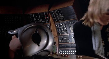 Movie still from “Phantom of the Paradise” (1974), directed by Brian De Palma – A person sitting in front of a bunch of electronic equipment; Medium shot, Low angle