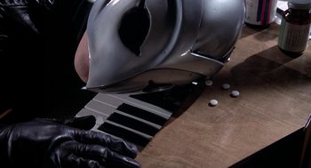 Movie still from “Phantom of the Paradise” (1974), directed by Brian De Palma – A person wearing a helmet and gloves on top of a piano; Extreme Close Up shot, Overhead angle