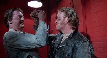 Movie still from “Phantom of the Paradise” (1974), directed by Brian De Palma – A man in a leather jacket holding his fist up; Close Up shot, Low angle